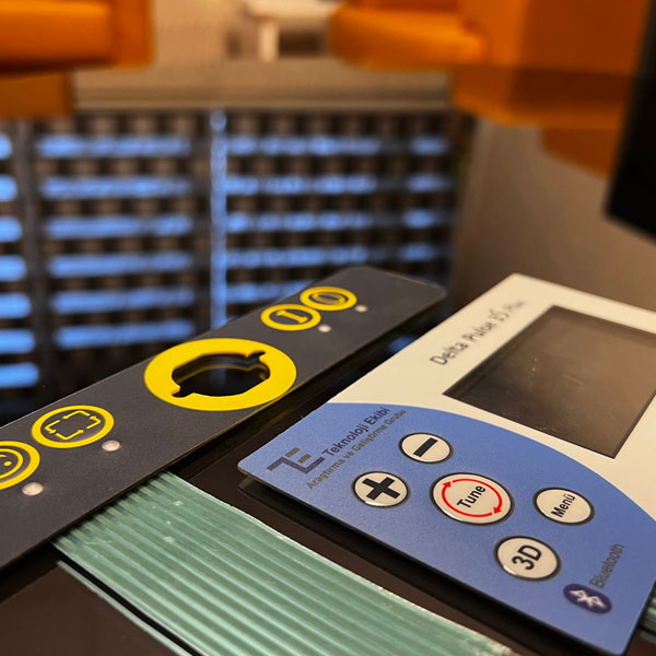 Blue membrane front panel for a device; LCD window, embossed round keys (Tune, Menu, 3D) and Bluetooth indicator, shown with a second black-and-yellow membrane panel.