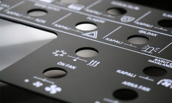 Vehicle HVAC control panel; laser-etched aluminium surface with fan, beacon and ventilation symbols, button cut-outs and function labels.